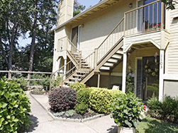 a house with stairs and a yard with bushes